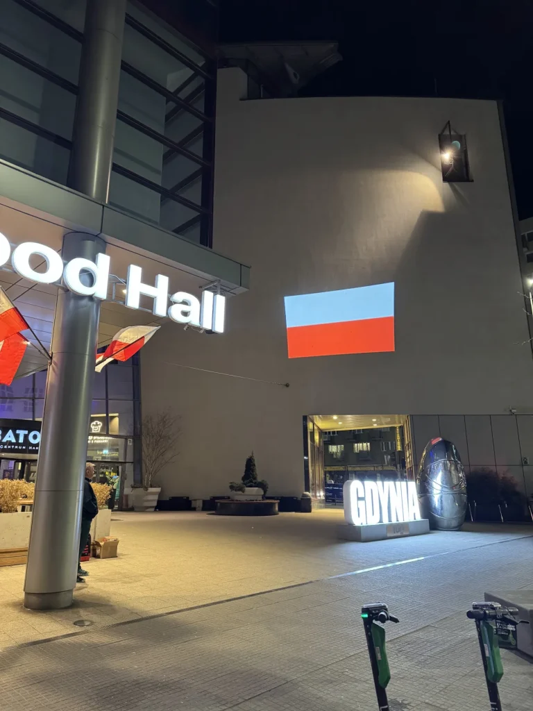 Flaga Polski wyświetlona projektorem GOBO na elewacji Galerii Batory