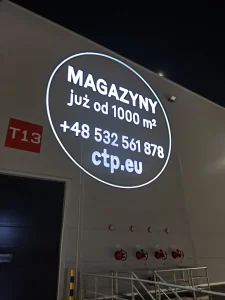 Reklama wynajmu magazynów wyświetlona projektorem GOBO na elewacji hali CTP w Warszawie