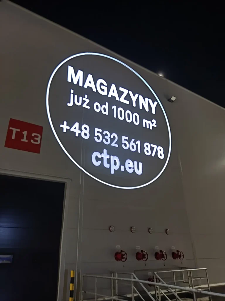 Reklama wynajmu magazynów wyświetlona projektorem GOBO na elewacji hali CTP w Warszawie