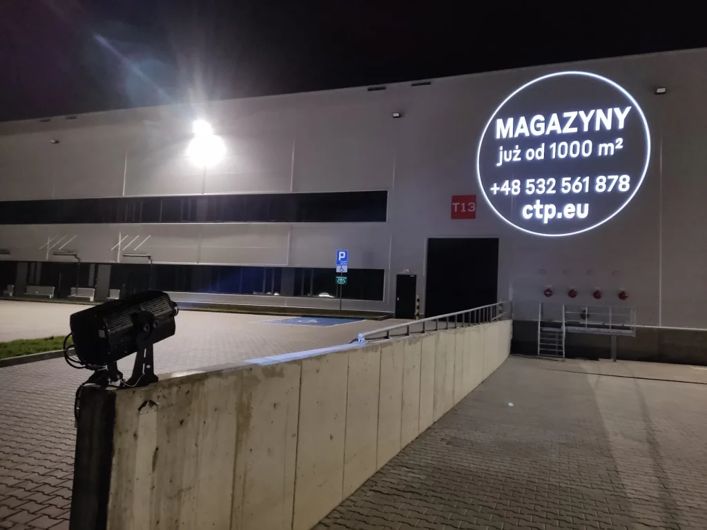 Projekcja GOBO na jasnej elewacji hali magazynowej po zmroku