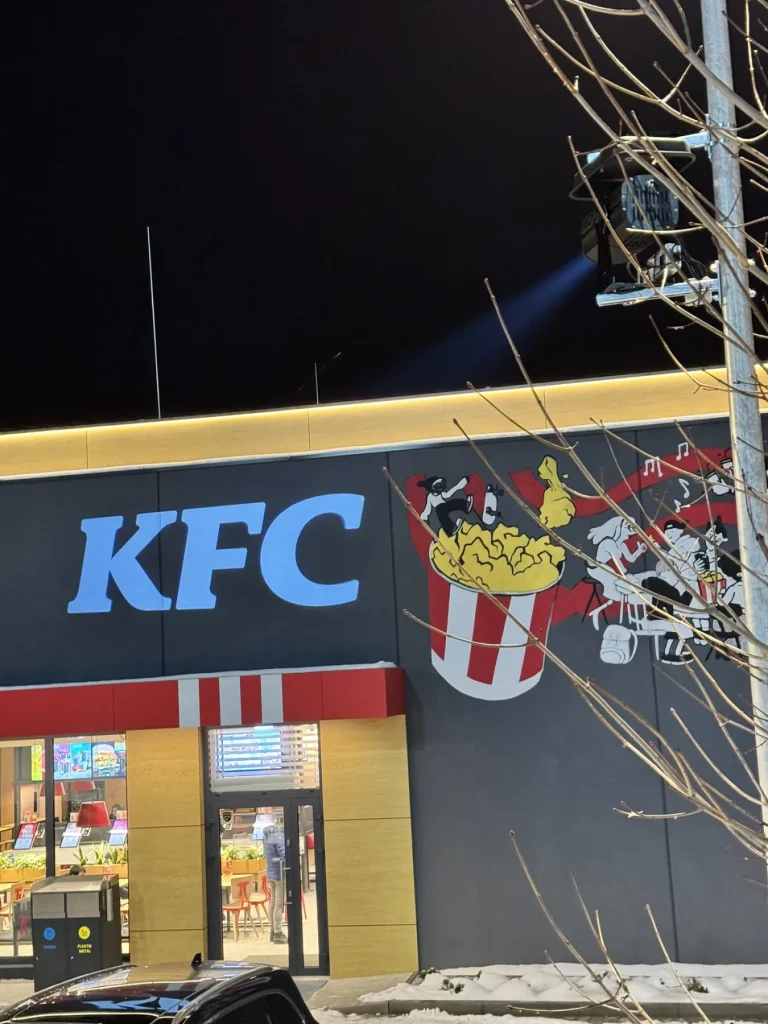 Logo KFC i grafiki sezonowe wyświetlone na elewacji restauracji zimą