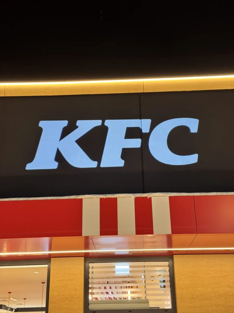 Zbliżenie na świetlną projekcję logo KFC na elewacji restauracji